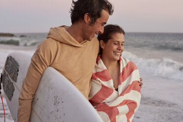 Lächelndes junges Paar am Strand mit Surfbrett - WESTF22075