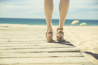 Legs of woman standing at boardwalk on the beach - CHPF00351