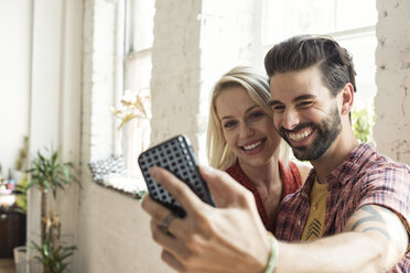Happy young couple taking a selfie in a loft - WESTF22109