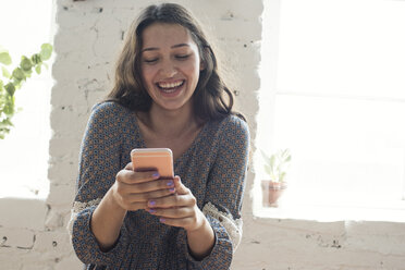 Glückliche junge Frau schaut auf ihr Handy - WESTF22112