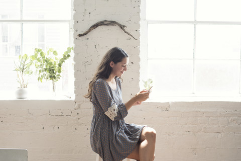 Smiling young woman looking on cell phone in a loft stock photo