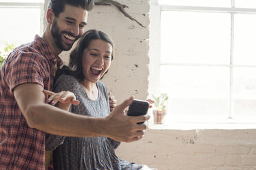 Verspieltes junges Paar macht ein Selfie in einem Loft - WESTF22116