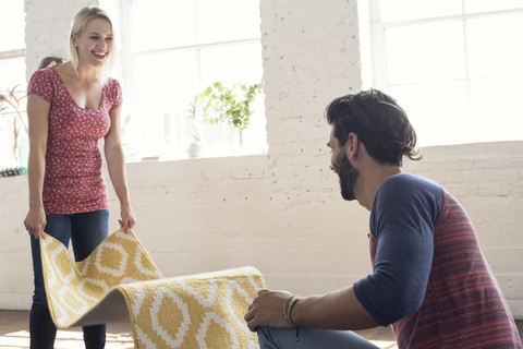 Young couple placing carpet in a loft stock photo