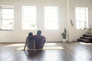 Junges Paar sitzt auf Teppich in einem Loft - WESTF22120