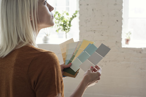 Junge Frau in einem Loft, die über Farbmuster nachdenkt, lizenzfreies Stockfoto