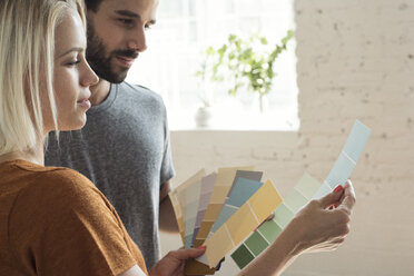 Young couple in a loft looking at color samples - WESTF22124