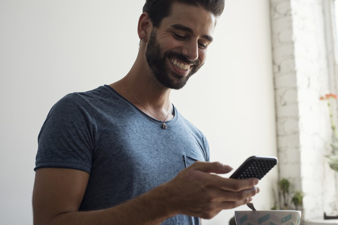 Smiling young man looking on cell phone stock photo