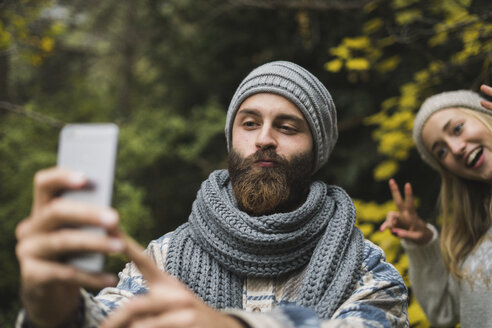 Verspieltes junges Paar im Freien im Herbst nehmen ein Selfie - KKAF00092