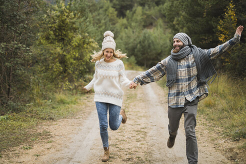 Glückliches junges Paar, das im Herbst auf einem Weg läuft - KKAF00094