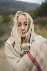 Portrait of young woman wrapped in a blanket outdoors - KKAF00098