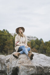 Junge Frau mit Hut auf einem Felsen sitzend - KKAF00101