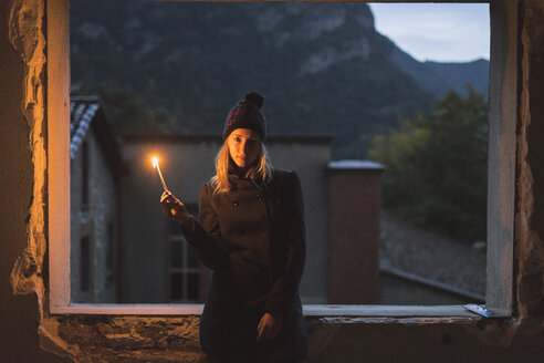 Junge Frau leuchtet in der Dämmerung mit einem Licht - KKAF00104