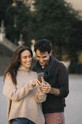 Laughing couple looking at cell phone - KKAF00118