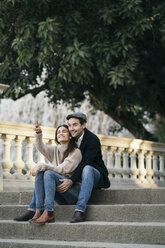 Couple in love sitting on steps watching something - KKAF00120