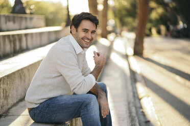 Portrait of laughing man sitting on stairs - KKAF00130