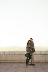 Verliebtes Paar umarmt sich auf einer Terrasse - KKAF00134