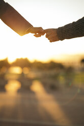 Verliebtes Paar hält sich bei Sonnenuntergang die Hände, Teilansicht - KKAF00141