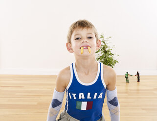 Porträt eines kleinen Jungen, der mit seinem Mund Pommes frites hält - FSF00630