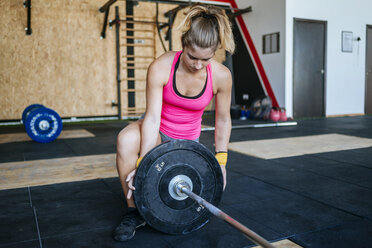Woman preparing barbell in gym - KIJF00919