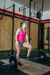 Woman resting on a barbell in gym - KIJF00921