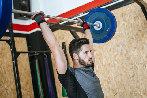 Mann hebt Langhantel im Fitnessstudio, lizenzfreies Stockfoto