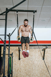 Mann macht Übungen an Ringen im Fitnessstudio - KIJF00938