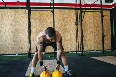 Mann bereitet sich auf das Heben von Kettlebells im Fitnessstudio vor - KIJF00943