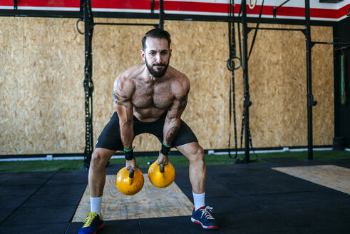 Mann hebt Kettlebells im Fitnessstudio - KIJF00944