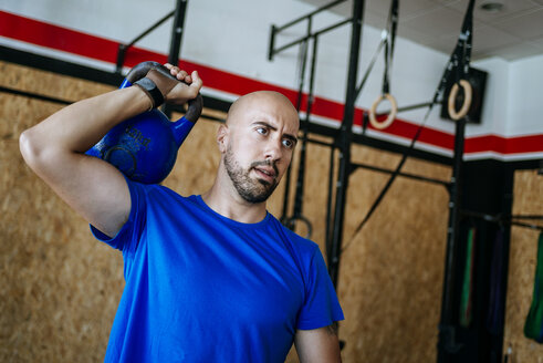 Mann hebt Kettlebell im Fitnessstudio - KIJF00946