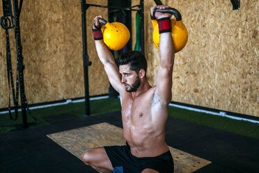 Mann hebt Kettlebells im Fitnessstudio - KIJF00948