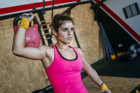 Frau hebt Kettlebell im Fitnessstudio, lizenzfreies Stockfoto