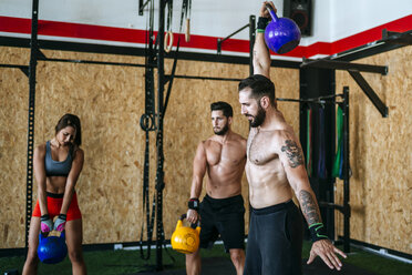 Group of athletes lifting kettlebells in gym - KIJF00956