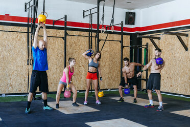 Gruppe von Athleten hebt Kettlebells im Fitnessstudio - KIJF00957