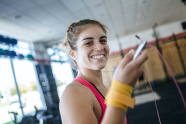 Portrait of smiling woman holding skipping rope in gym - KIJF00964