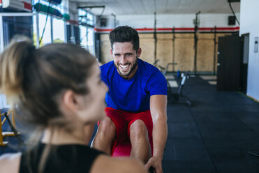 Lächelnder Mann sieht Frau im Fitnessstudio an - KIJF00969