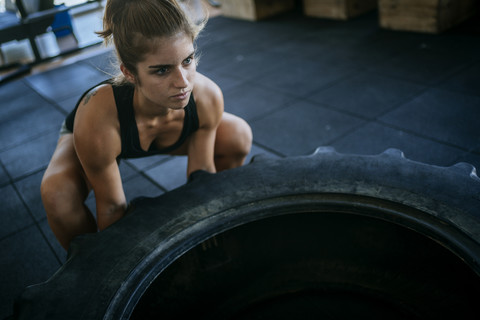 Frau trainiert mit einem Traktorreifen im Fitnessstudio, lizenzfreies Stockfoto