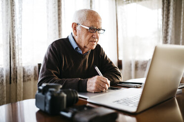 Senior-Fotograf arbeitet mit Laptop zu Hause - JRFF01051