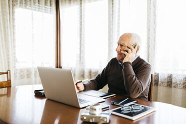 Senior-Fotograf am Telefon zu Hause - JRFF01059