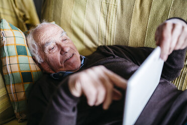 Älterer Mann auf Couch liegend mit Tablet - JRFF01067