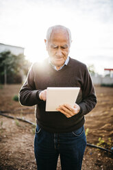 Älterer Mann benutzt Tablet im Garten - JRFF01074