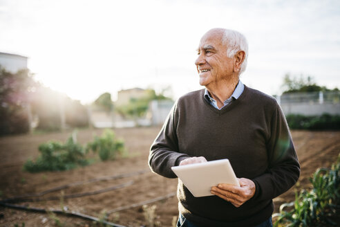 Glücklicher älterer Mann mit Tablet im Garten - JRFF01075