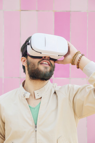 Mann mit Virtual-Reality-Brille vor der rosa Wand, lizenzfreies Stockfoto