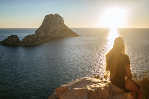 Spanien, Ibiza, Frau mit Blick auf das Meer und die Insel Es Vedra bei Sonnenuntergang - KIJF01020