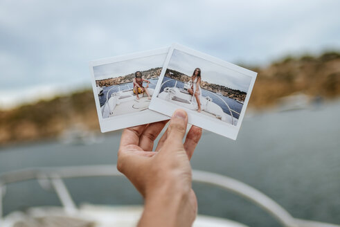 Spain, Ibiza, Hand holding images of man and woman on motor boat - KIJF01030