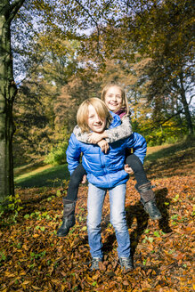 Porträt eines Jungen, der seine Schwester im Herbst Huckepack nimmt - SARF03076