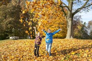 Brother and sister throwing autumn leaves in the air - SARF03080