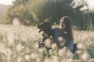 Young woman and her dog in field of flowers at twilight - SKCF00224