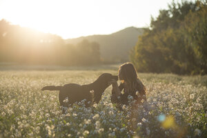 Junge Frau und ihr Hund in einem Blumenfeld in der Dämmerung - SKCF00226