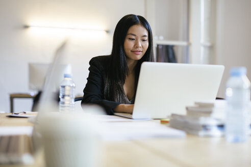 Junge asiatische Frau arbeitet im Büro mit Laptop - EBSF01910