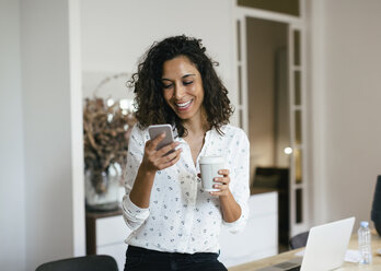 Businesswoman in office using smart phone, holding cup of coffee - EBSF01936